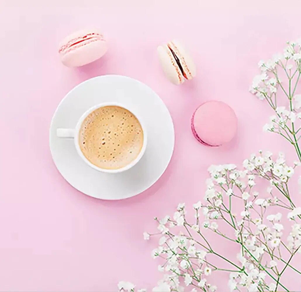 Fondo rosa con macarons y taza de café